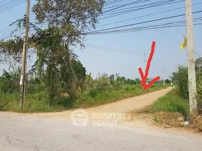 Vacant land plot with potential for development, surrounded by greenery and accessible via dirt road.