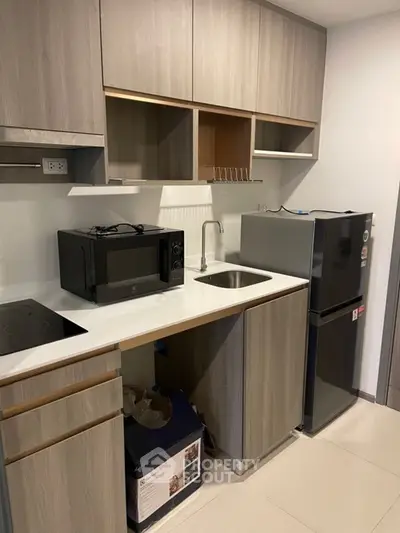 Modern compact kitchen with sleek cabinetry and appliances in a stylish apartment.