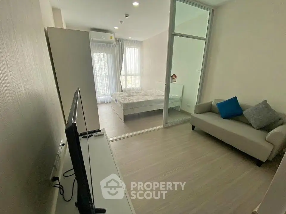 Modern apartment interior with cozy living room and bedroom, featuring sleek furniture and natural light.