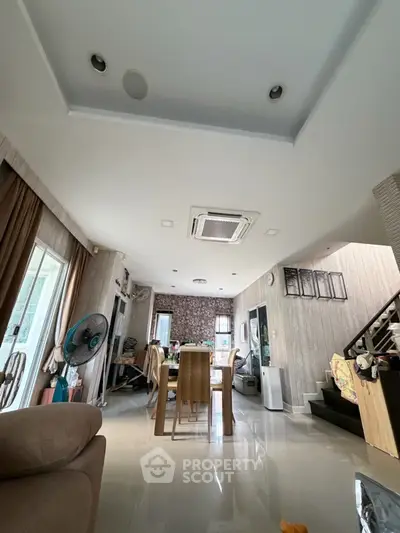 Spacious modern living room with dining area and staircase, featuring elegant decor and ample natural light.