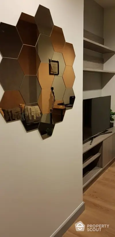 Modern living space with unique hexagonal mirror wall art, sleek floating shelves, and a flat-screen TV, blending functionality with style.