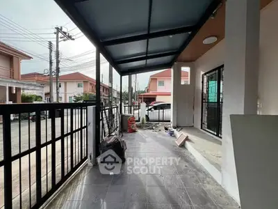 Spacious covered patio area in suburban home with tiled flooring and modern railing.