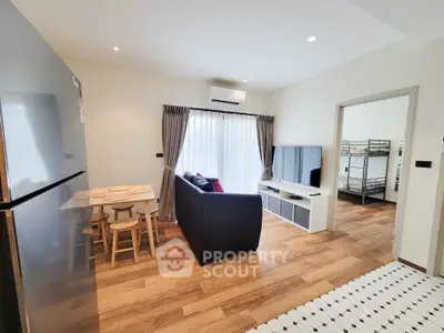 Modern living room with sleek furniture and wooden flooring, featuring a cozy dining area and large window.