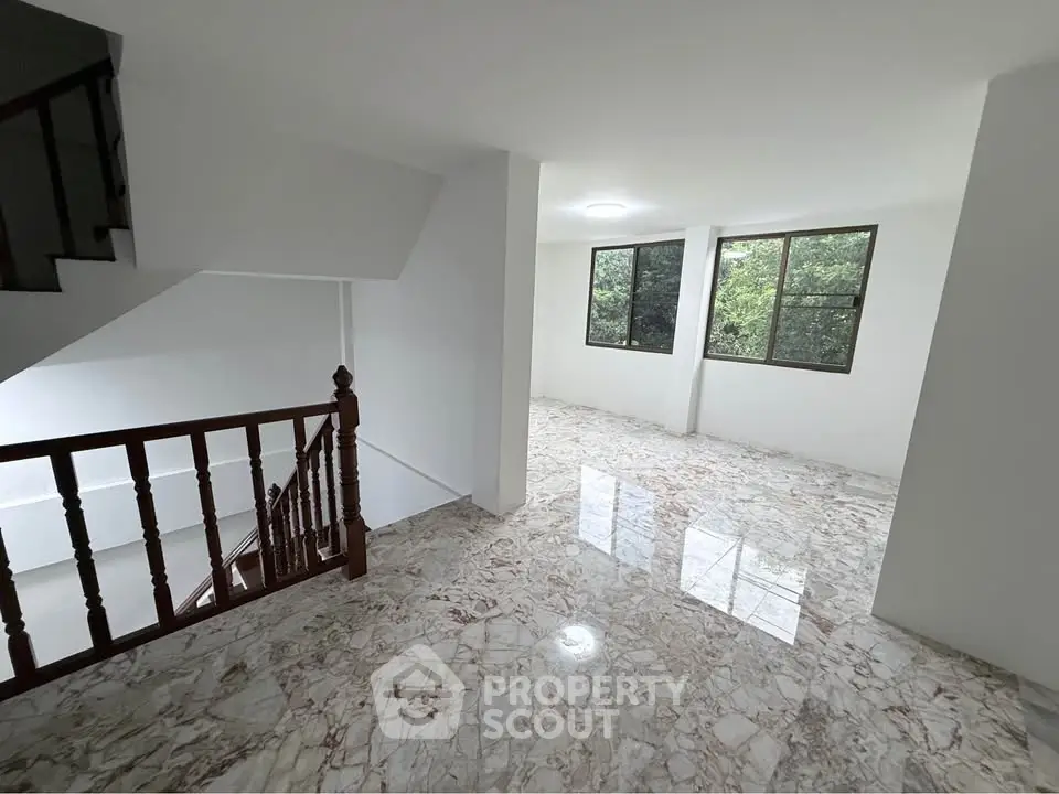 Spacious marble-floored interior with large windows and staircase, offering natural light and modern elegance.