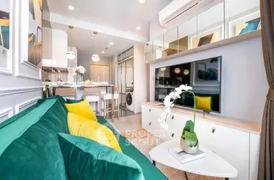 Modern living room with vibrant green sofa, large TV, and stylish decor in open-plan apartment.