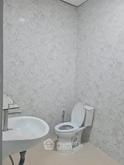 Modern minimalist bathroom with marble walls and white fixtures