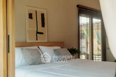 Cozy bedroom with modern decor and natural light through large windows.