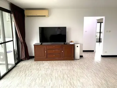 Spacious living room with modern TV setup and large windows for natural light.