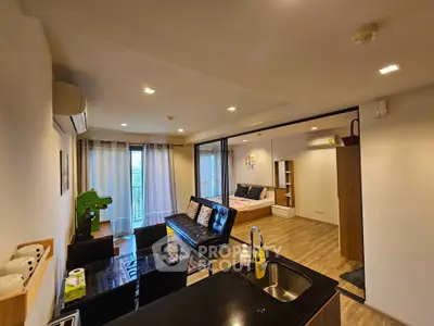 Modern open-plan living room with dining area and cozy bedroom, featuring sleek furnishings and natural light.