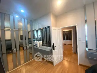 Spacious modern bedroom with mirrored wardrobe and sleek wooden flooring