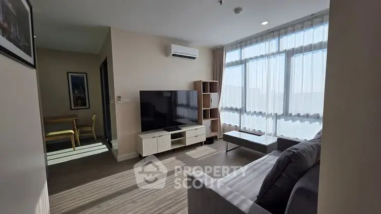 Modern living room with large windows, sleek furniture, and abundant natural light in a stylish apartment.