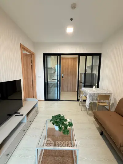 Modern living room with sleek furniture and glass partition leading to kitchen