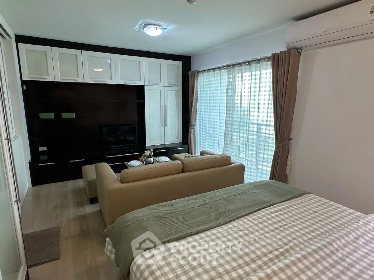 Cozy studio apartment with modern living area and large windows for natural light.