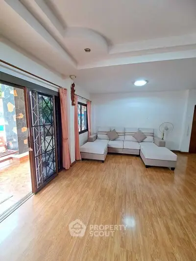 Spacious living room with wooden flooring and large windows for natural light.