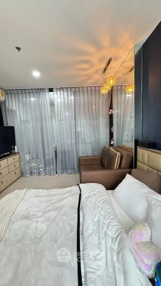 Luxurious bedroom with elegant decor and cozy seating area, featuring modern lighting and floor-to-ceiling windows.