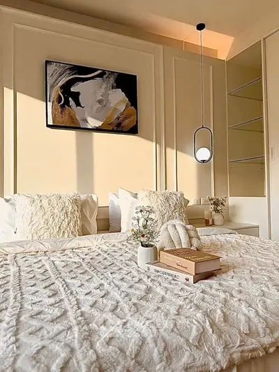 Luxurious bedroom with elegant decor and soft lighting, featuring plush bedding and modern artwork.