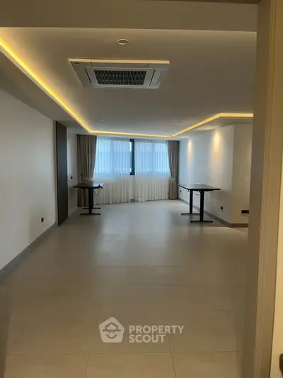 Spacious modern living room with large windows and elegant lighting, perfect for stylish urban living.