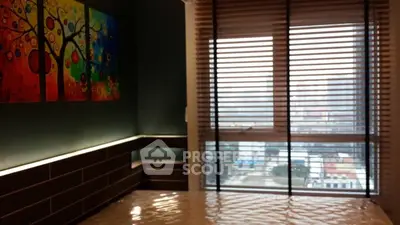 Modern bedroom with large window and vibrant wall art, offering city views.