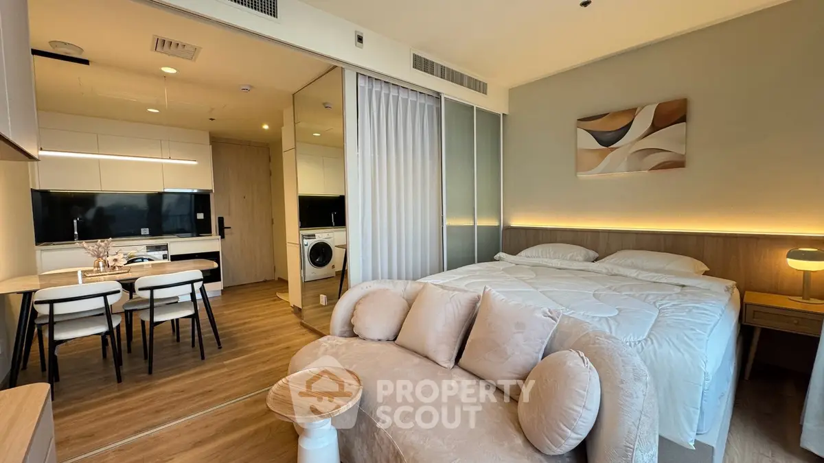 Modern studio apartment with cozy living area and kitchen, featuring stylish decor and natural lighting.