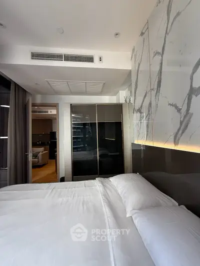 Luxurious bedroom with modern design and marble accent wall, featuring a spacious bed and sleek wardrobe.