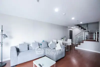 Spacious modern living room with stylish gray sofa and elegant staircase in a contemporary home.