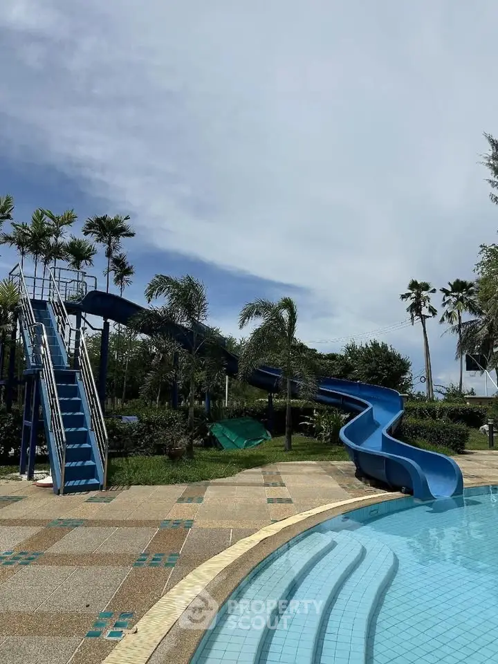 Luxurious outdoor pool with water slide in tropical resort setting