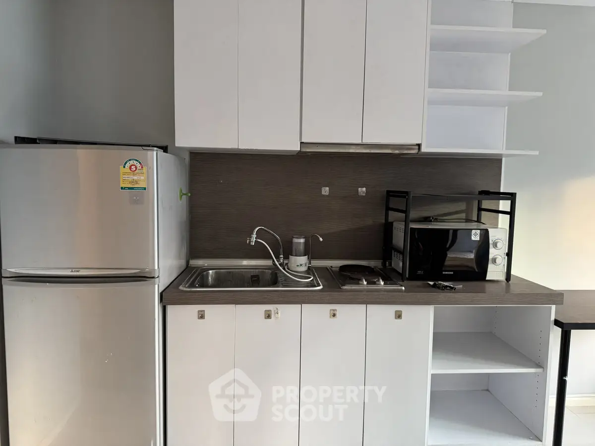 Modern kitchen with sleek cabinets, stainless steel fridge, and microwave, perfect for urban living.
