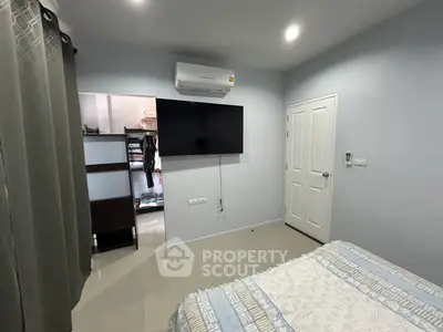 Modern bedroom with wall-mounted TV and air conditioning, featuring a sleek design and cozy atmosphere.