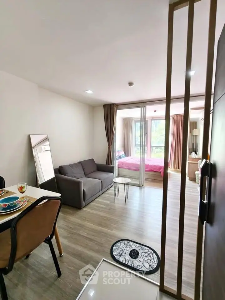 Modern open-plan living room with cozy seating and bedroom view, perfect for urban living.