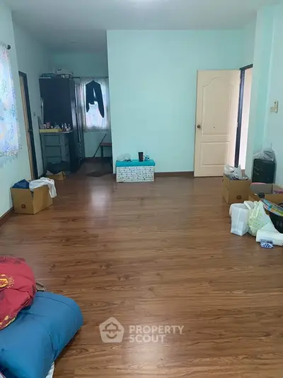 Spacious empty room with wooden flooring and minimal furniture, ideal for customization.