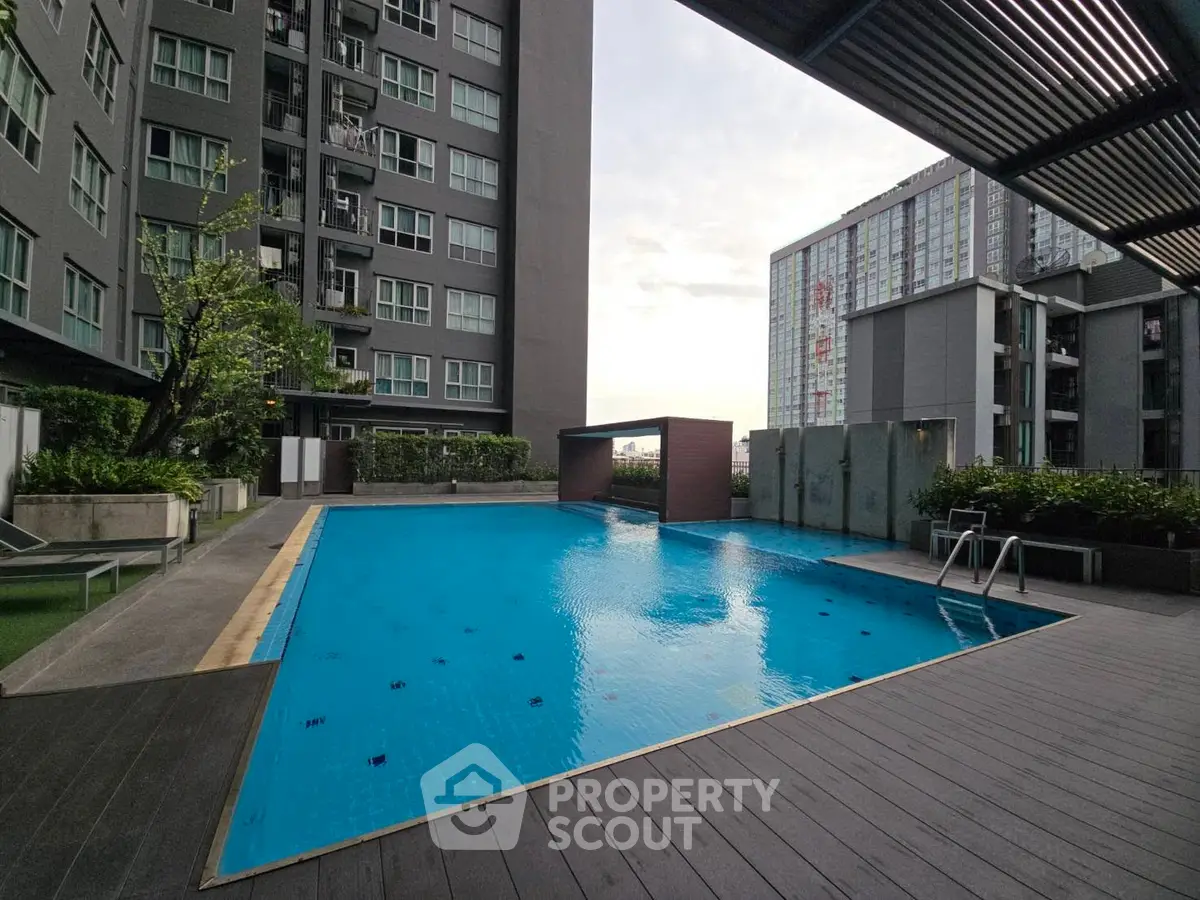 Modern apartment complex with a sleek outdoor pool and urban skyline view.
