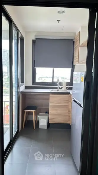 Modern kitchen with sleek design, featuring large window and compact layout in urban apartment.