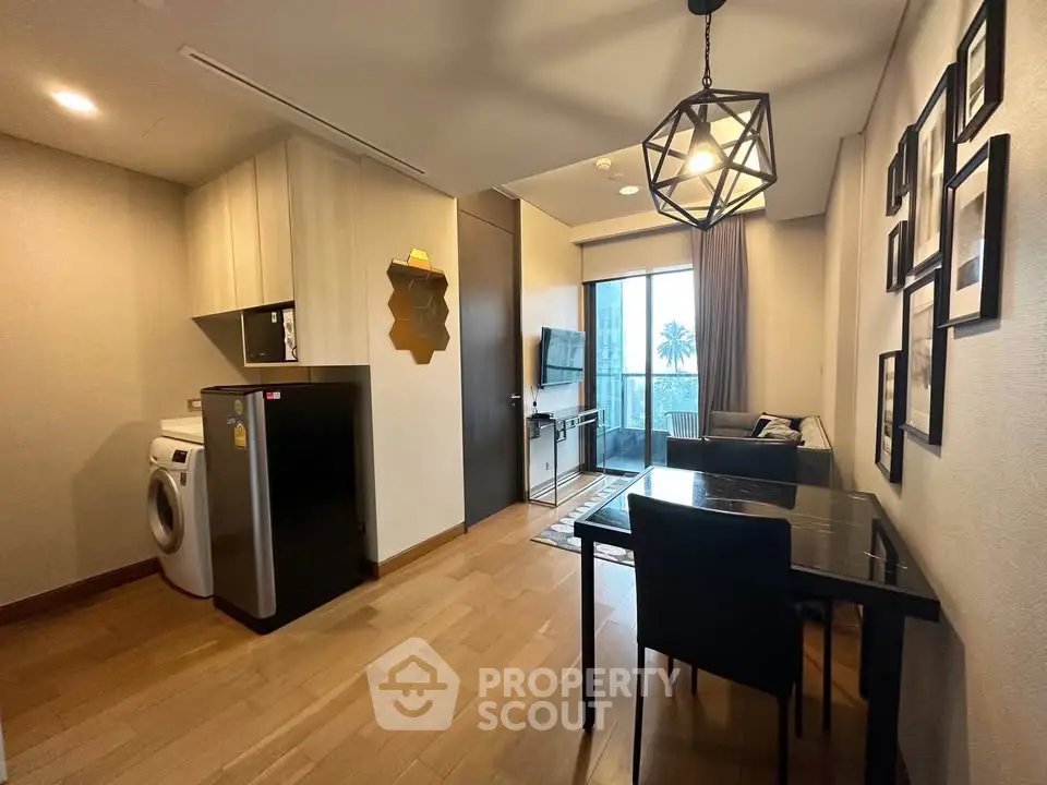 Modern living room with stylish decor, compact kitchen, and balcony view in urban apartment.