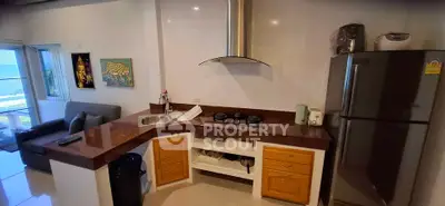 Modern kitchen with gas stove and ocean view, featuring sleek countertops and cozy living area.