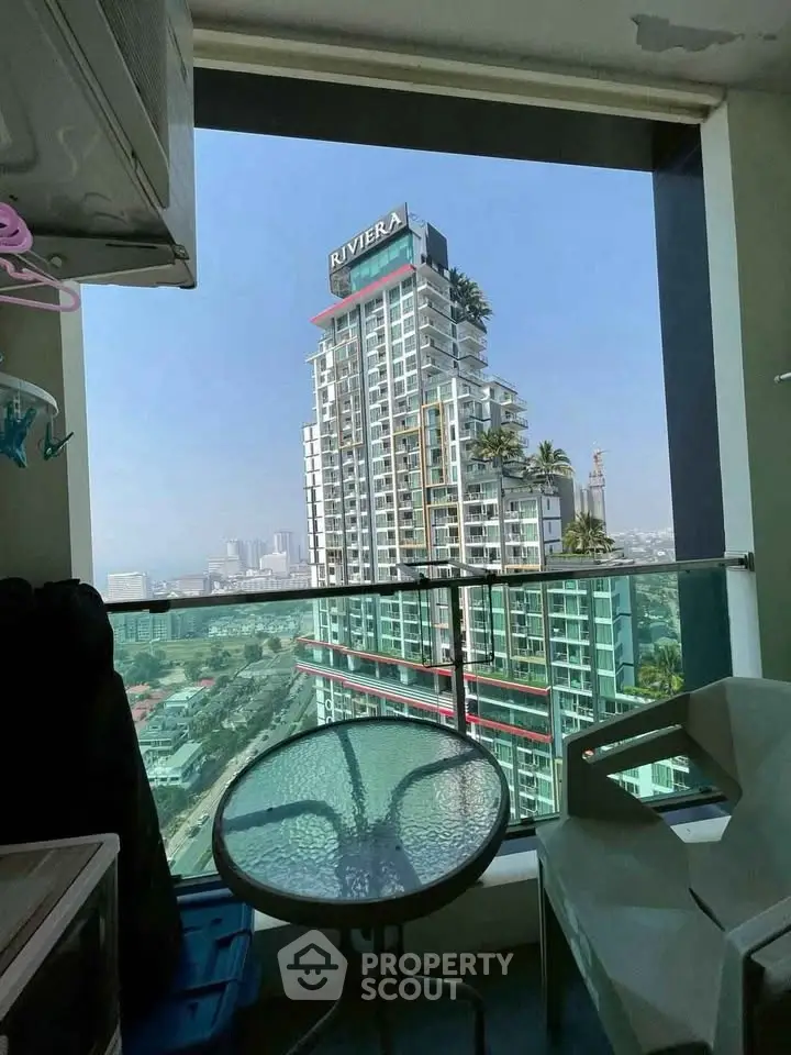 Stunning high-rise building view from a modern balcony with glass railing and outdoor seating.