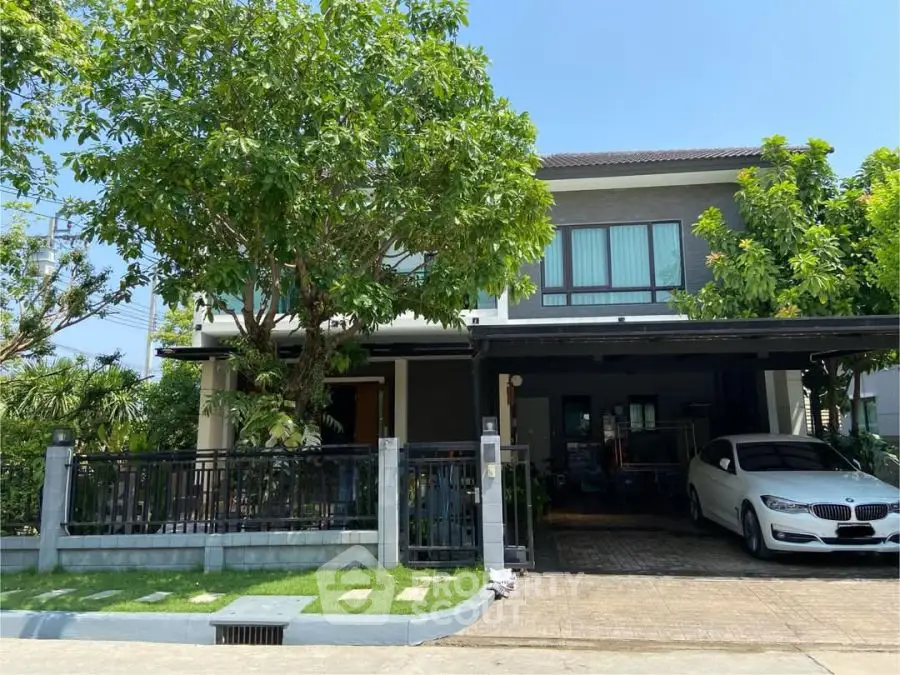 Charming two-story house with lush garden and carport in a serene neighborhood.