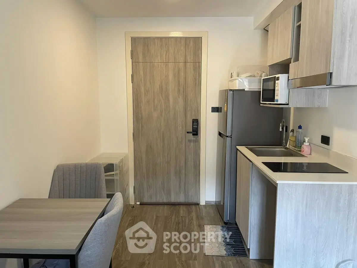 Compact modern kitchen with sleek appliances and cozy dining area in stylish apartment.