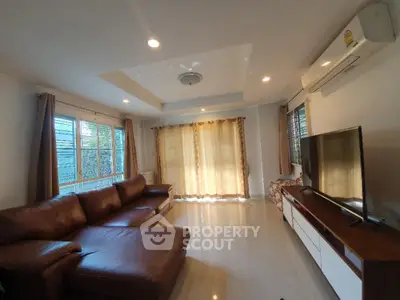 Spacious living room with modern leather sofa and large TV, perfect for relaxation.