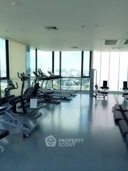 Spacious gym with panoramic city views and modern exercise equipment.