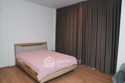 Spacious bedroom with wooden flooring and elegant curtains