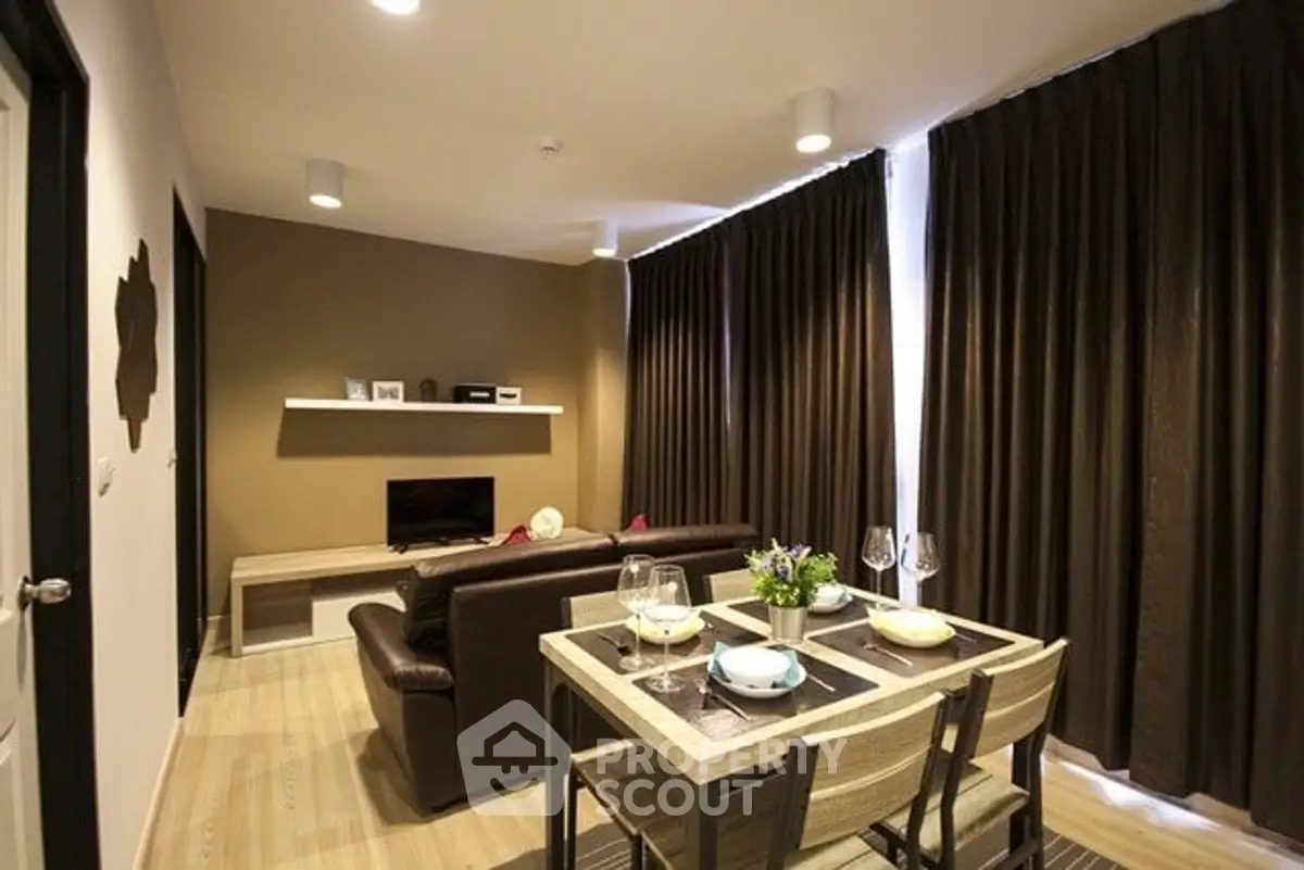 Cozy living room with modern decor and dining area, featuring elegant lighting and stylish furnishings.