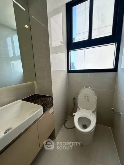 Modern bathroom with sleek fixtures and large window offering natural light.