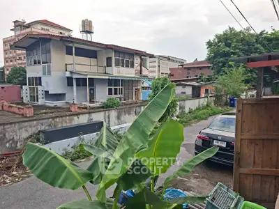 Urban residential area with a two-story building and surrounding greenery, showcasing potential for development.