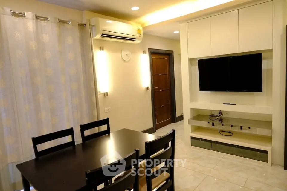 Modern living room with dining area, wall-mounted TV, and air conditioning.