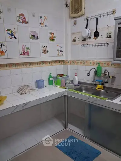 Charming kitchen with playful animal-themed tiles and modern stainless steel sink.