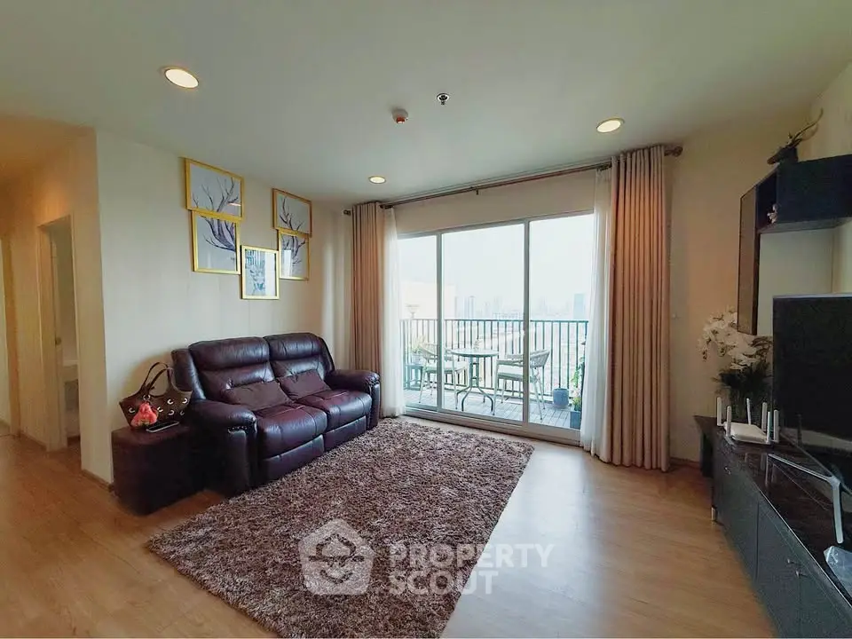 Spacious living room with balcony and city view, featuring modern decor and comfortable seating.