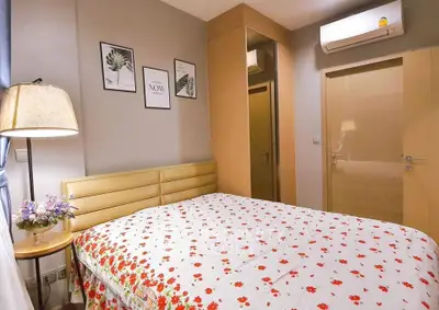 Cozy bedroom with floral bedding and modern decor, featuring air conditioning and soft lighting.