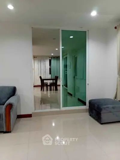 Spacious living room with modern furniture and sliding glass doors leading to dining area.
