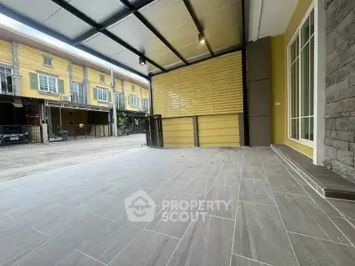 Spacious modern patio with sleek tile flooring and covered roof in urban townhouse setting.