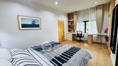 Spacious bedroom with modern decor and study area, perfect for comfort and productivity.